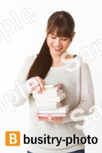 本の山を手にする女性
