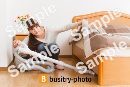 ベッドの下を掃除する女性