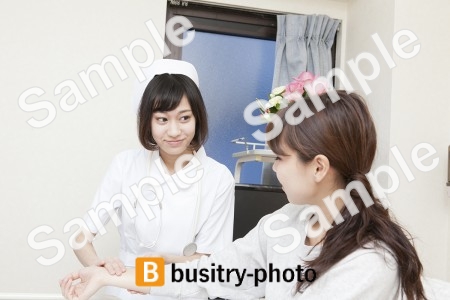 女性患者の脈を測る看護師