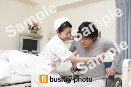 車椅子に乗る男性患者を介護する看護師