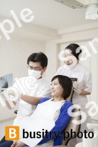 女性患者にレントゲンを説明する歯科医と歯科助手