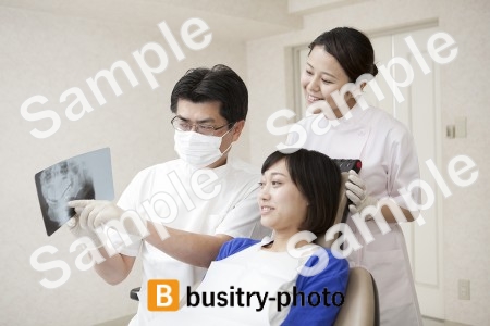 女性患者にレントゲンを説明する歯科医と歯科助手