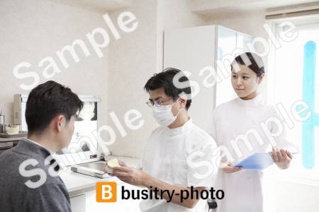 男性患者に説明をする歯科医と歯科助手