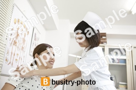 女性患者の肩を抑える看護師